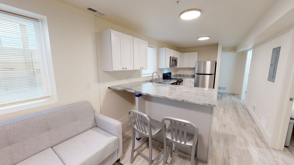 A kitchen with a grey couch and a marble countertop.