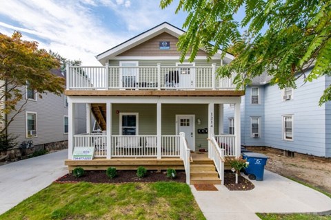 A house with a front porch and a sign that says "For Sale".
