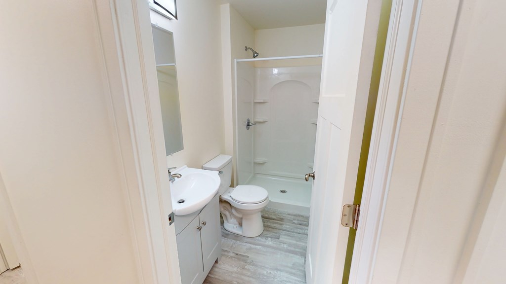 A white bathroom with a toilet, sink, and shower.