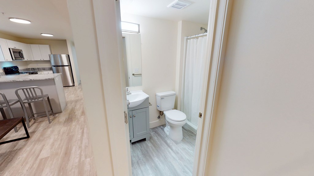 A bathroom with a toilet and sink is visible through a doorway.
