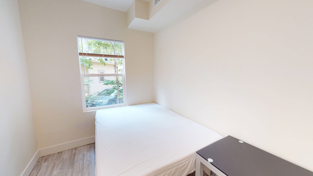 A bedroom with a bed, desk, and window.