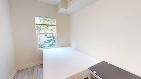 A bedroom with a bed, desk, and window.