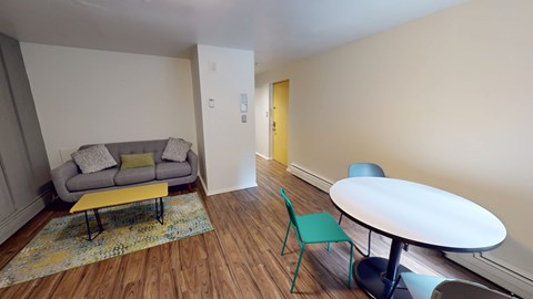 A living room with a grey couch, yellow coffee table, and a green chair.