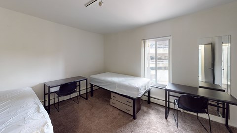 A bedroom with a bed, desk, and chair.
