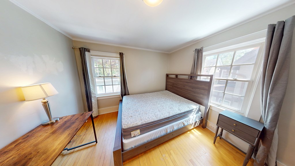 A bedroom with a bed, nightstand, and window.