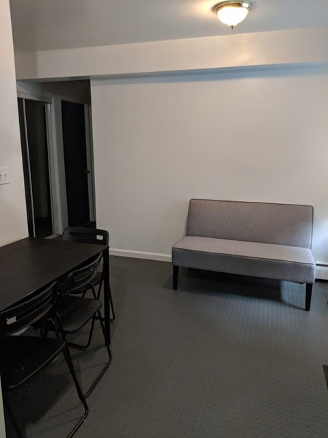 A grey sofa sits in a room with a black table and chairs.