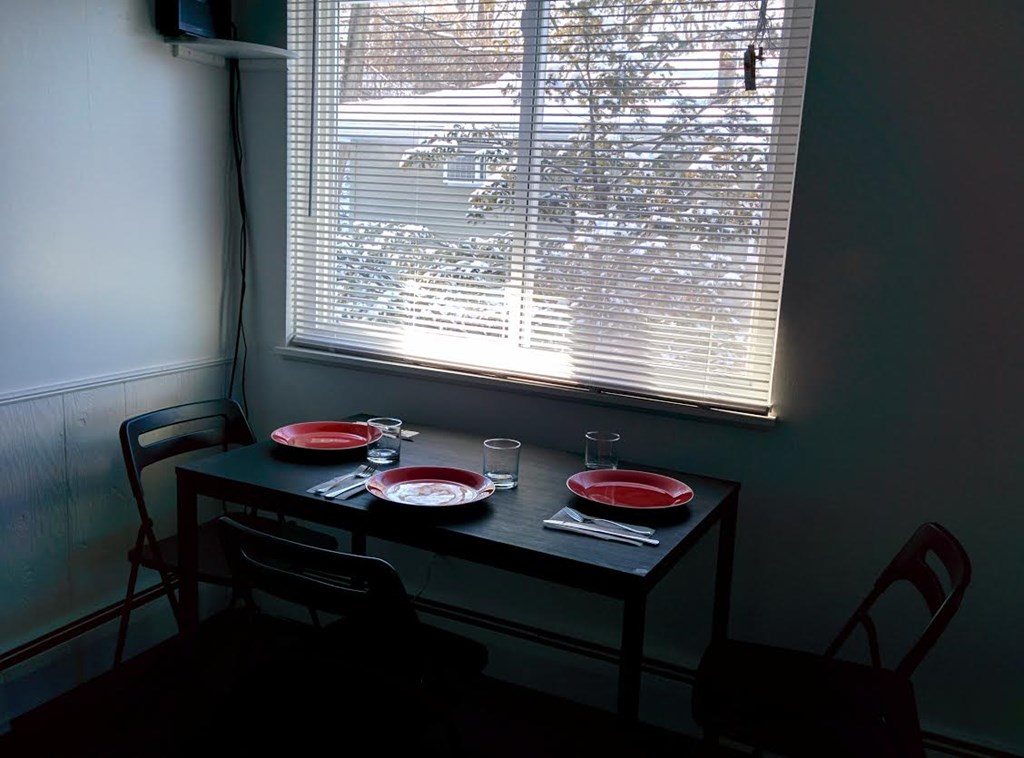 A table with two chairs and a meal set up by a window.