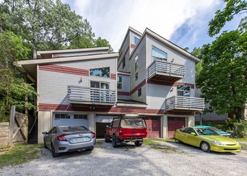 A two-story house with a garage and three cars parked in front.