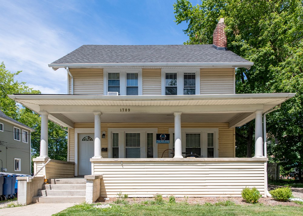 A two-story house with a front porch and a chimney.