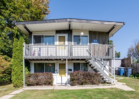 A two-story house with a balcony and stairs leading to the second floor.