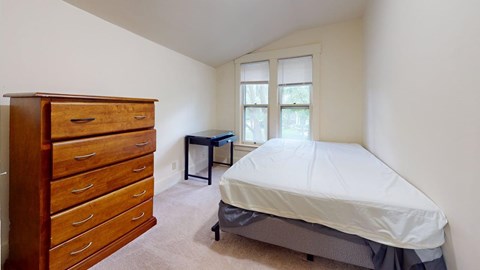 A bedroom with a bed, dresser, and desk.