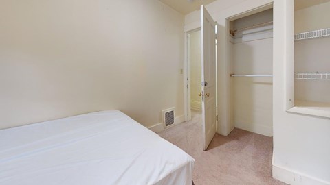 A bedroom with a bed, closet, and a door leading to another room.