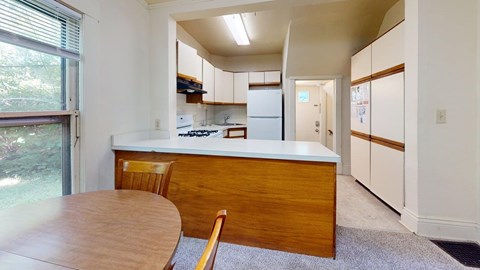 A kitchen with a table and chairs in front of a window.