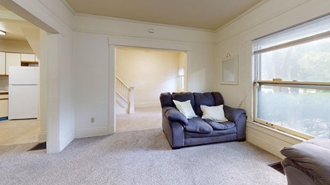 A living room with a blue couch and a grey carpet.