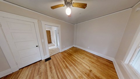 A room with a ceiling fan and wooden flooring.