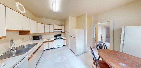 A kitchen with white cabinets and a wooden table.