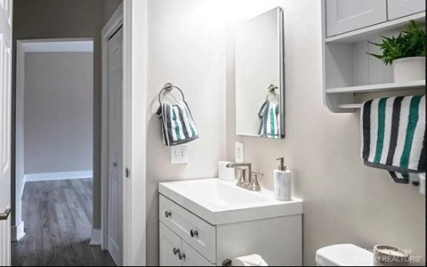 A white bathroom with a toilet, sink, and mirror.