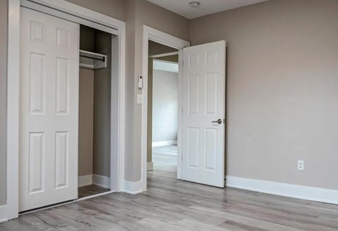 A room with two white doors and a wooden floor.