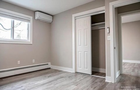 A room with a window, a door, and a wall-mounted air conditioner.