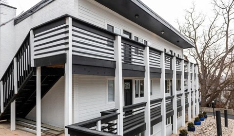 A white house with black stripes on the balcony.