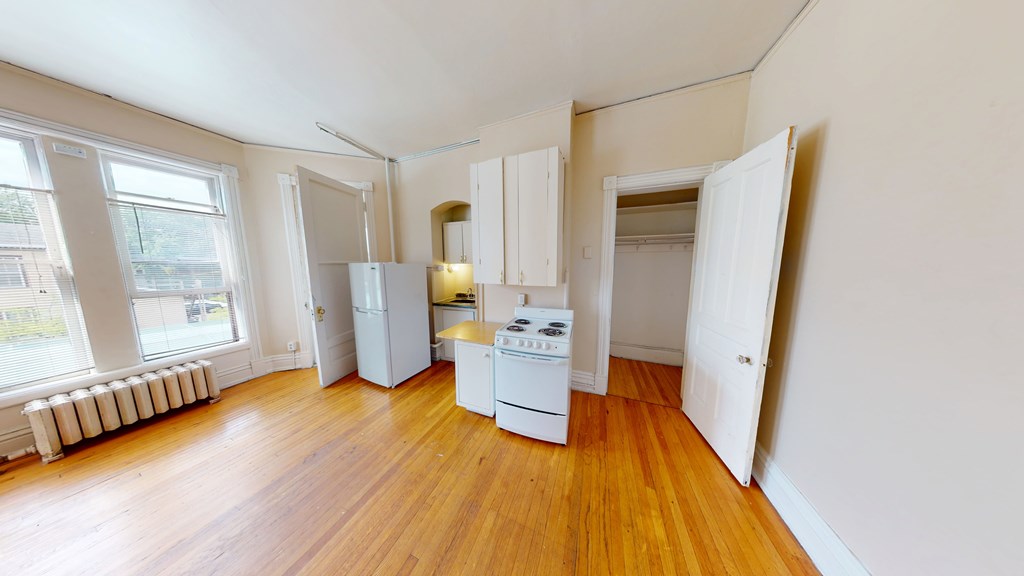 A kitchen with white appliances and wooden floors.