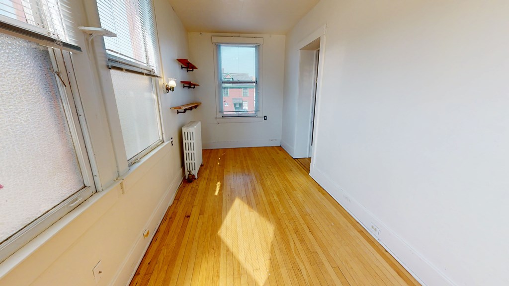 A room with a window and a radiator on the floor.