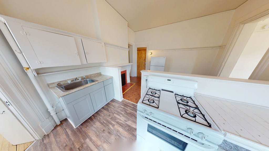 A kitchen with a white stove top oven and a sink.