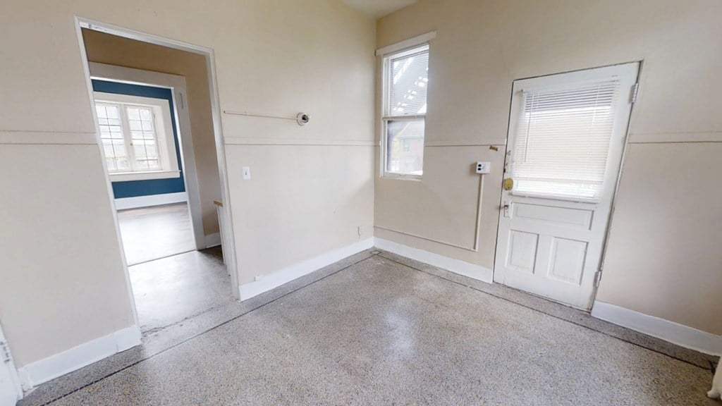 A room with a door, window, and a small opening to another room.