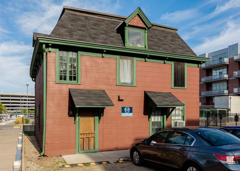 A red building with green trim and a car parked in front.