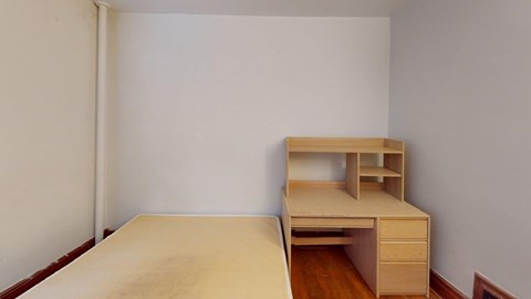 A wooden desk with drawers is in a room with white walls.