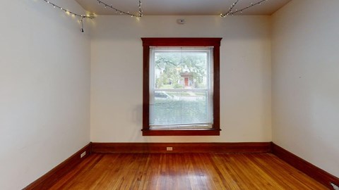 A room with wooden floors and a window showing a view of a street.