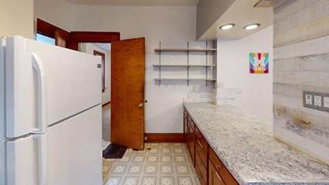 A kitchen with a white fridge and a white counter top.