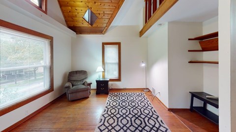 A living room with a wooden floor and a patterned rug.