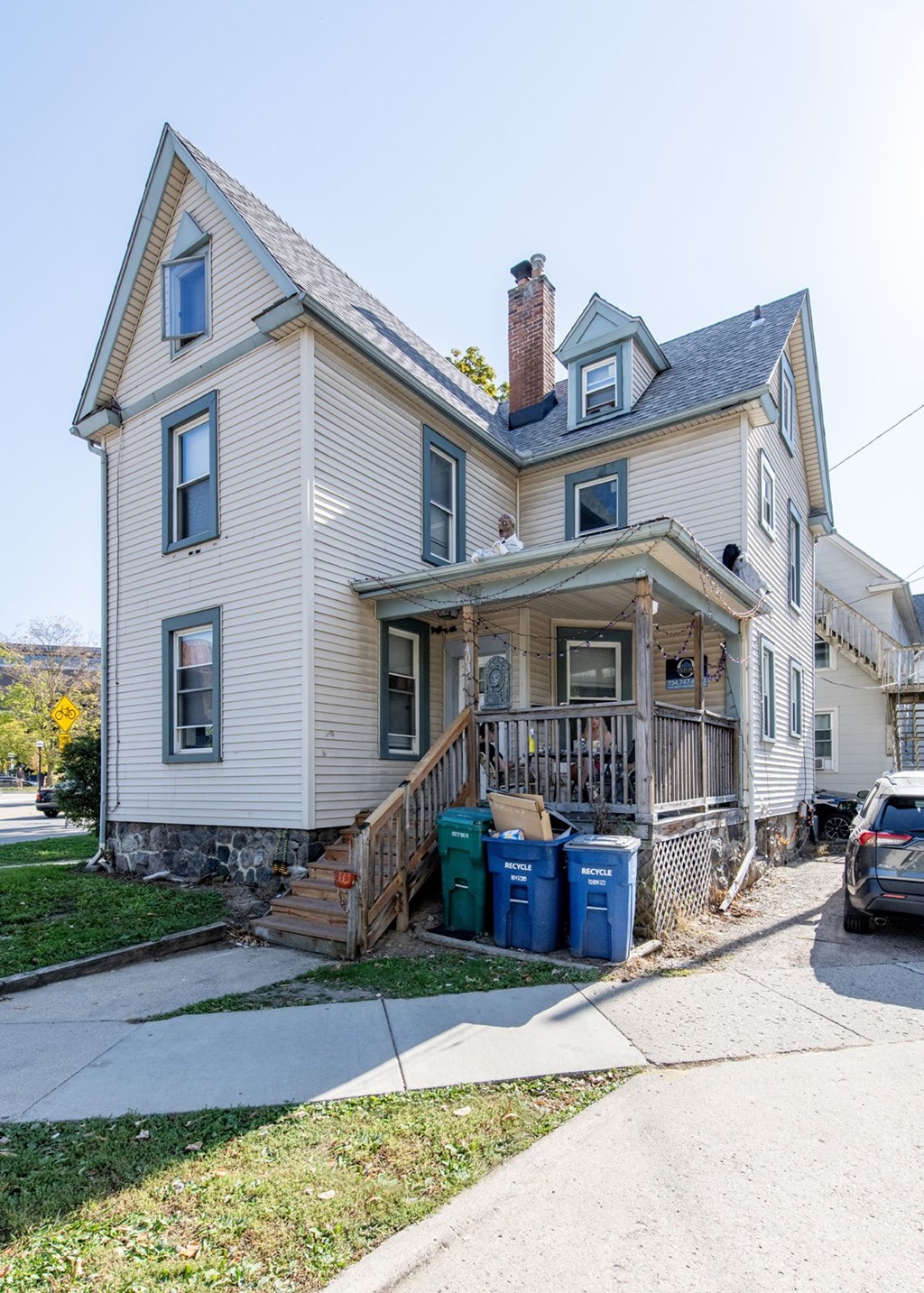 A two-story house with a front porch and a car parked in front.