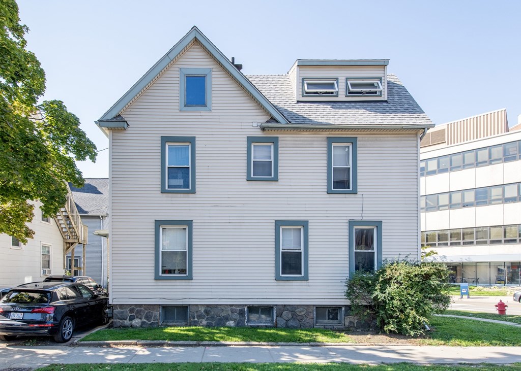 A house with a grey facade and a black car parked in front.