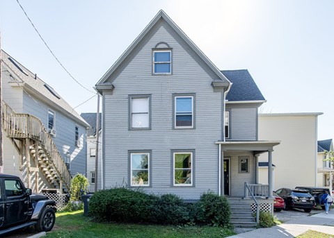 A two-story house with a grey exterior and a small front porch.