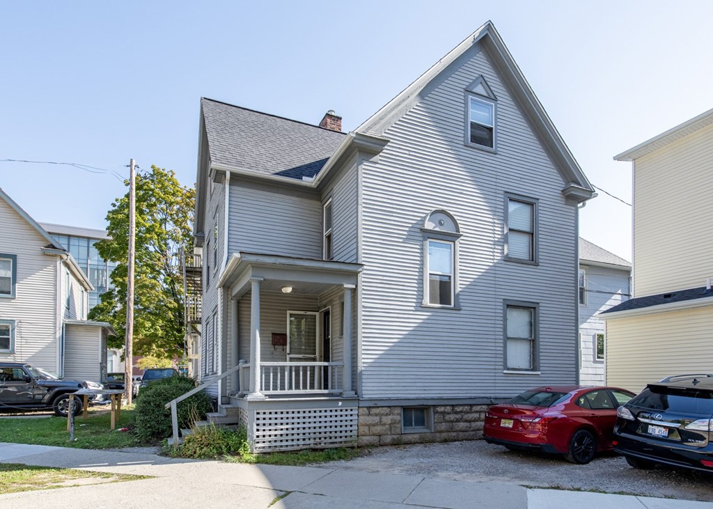 A grey house with a red car parked in front.