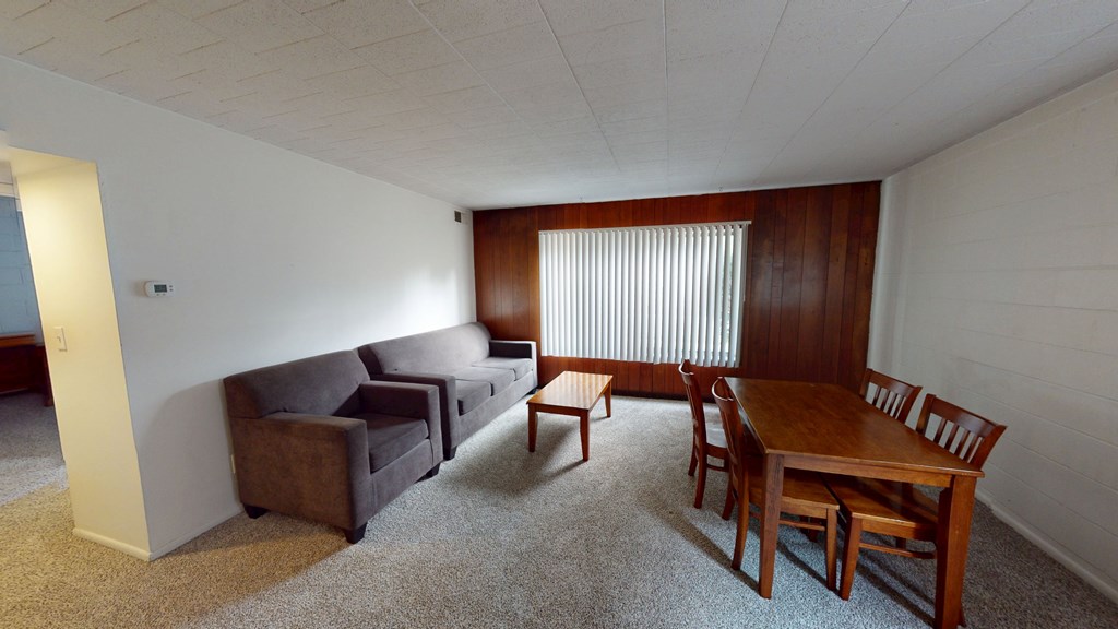 A living room with a brown couch, a brown chair, and a brown table.
