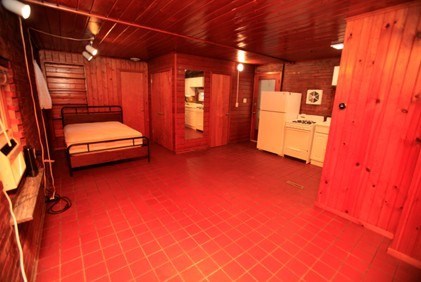 A room with a bed, a refrigerator, and a stove.