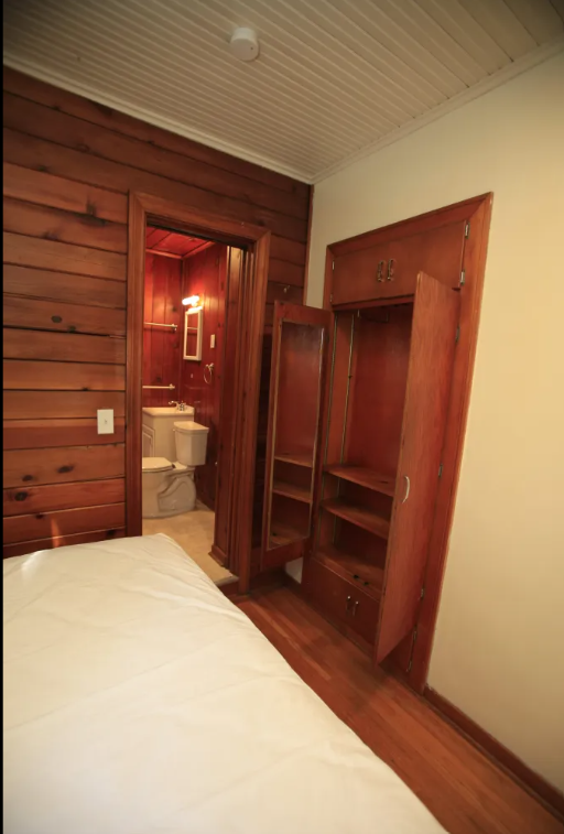 A bedroom with a bed, wooden dresser and a wooden wardrobe.