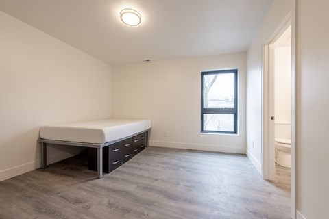 A bedroom with a bed, a window, and a door.