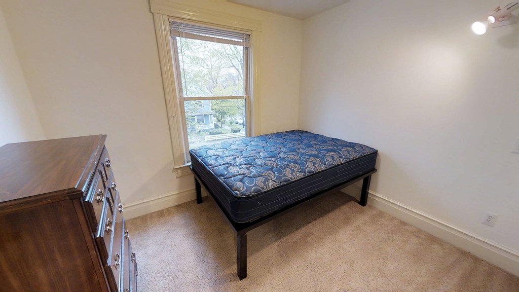 A bedroom with a bed, a window, and a staircase.
