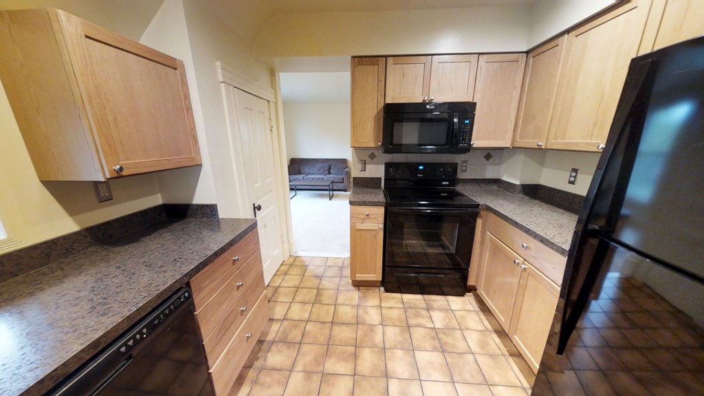 A kitchen with black appliances and wooden cabinets.
