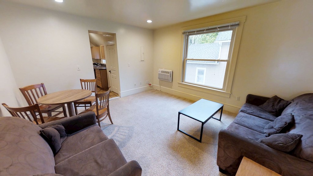 A living room with a brown couch, a coffee table, and a dining table.