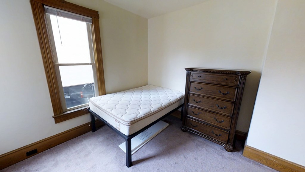 A bedroom with a bed and a dresser.