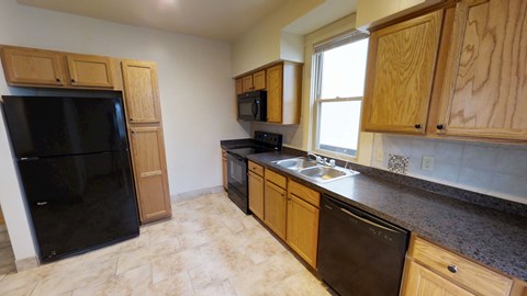 A kitchen with wooden cabinets and black appliances.