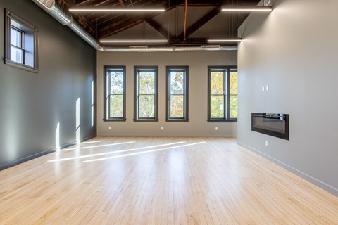 A spacious room with wooden floors and large windows.