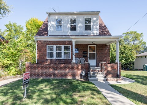 A house with a red brick facade and a white porch.