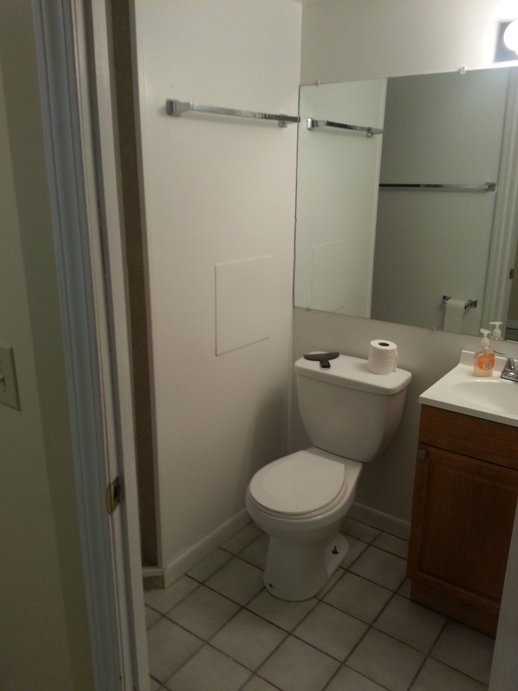 A white toilet in a small bathroom with a white sink and a mirror.