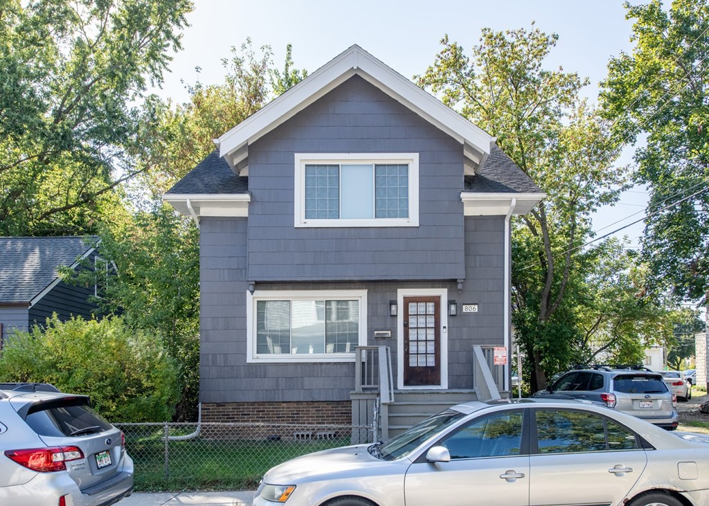 A grey house with a car parked in front.
